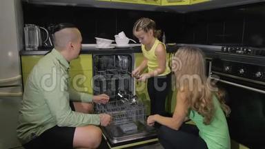 母亲和父亲教女儿学习使用洗碗机。 女主人把脏盘子装进去